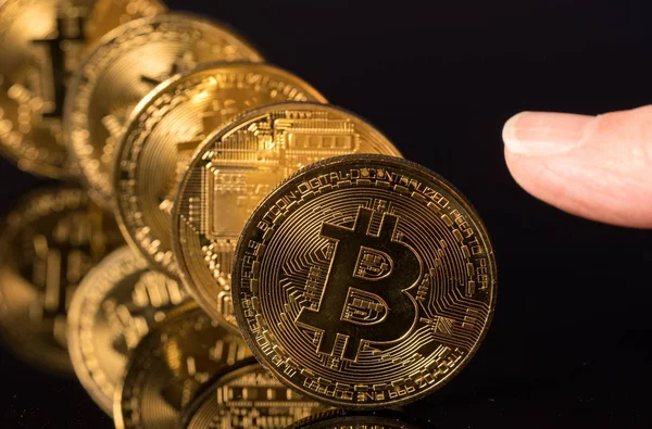 Bitcoins stehen in einer Reihe wie Dominosteine mit dem Finger — Stockfoto