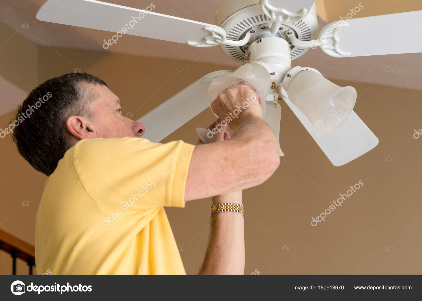Senior Caucasian Man Replacing Bulb In Ceiling Fan And Light