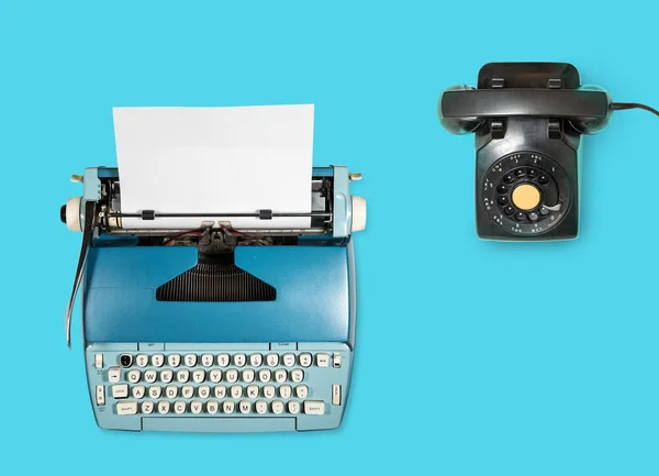 Старая электрическая печатная машинка и телефон на обычном фоне — стоковое фото