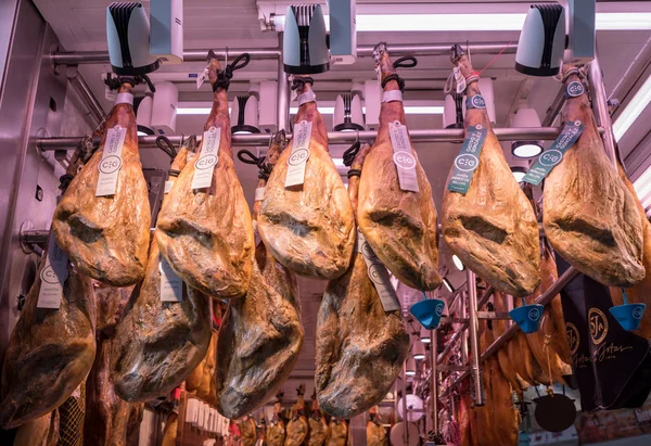 Hams iberici appesi alla bancarella del mercato a Valencia — Foto Stock
