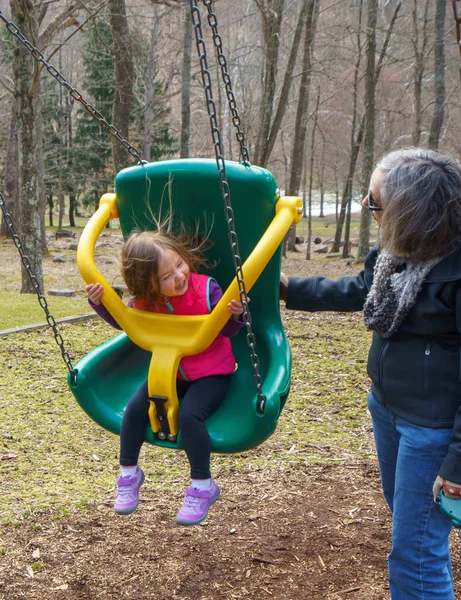 Nonna e nipote giocano in altalena di plastica — Foto Stock