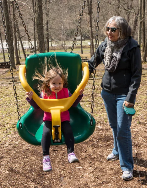 Nonna e nipote giocano in altalena di plastica — Foto Stock