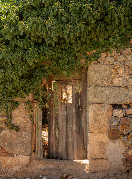 Wooden door opening into garden of stone house in the ancient town of Castelo Rodrigo in Portugal