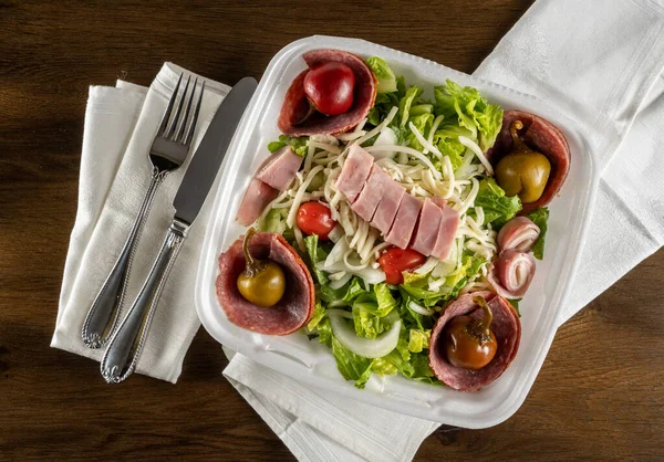 Antipastasalade met ham en salami en paprika 's in plastic afhaalcontainer — Stockfoto