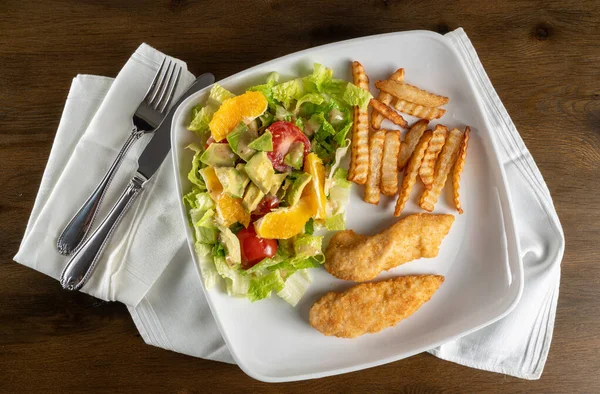 Плоский салат з картоплею фрі та курячими тендерами, розташованими на тарілці — стокове фото