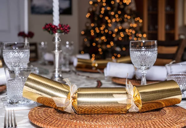 Traditional family Christmas lunch table set with crackers with tree in background — Stock Photo, Image