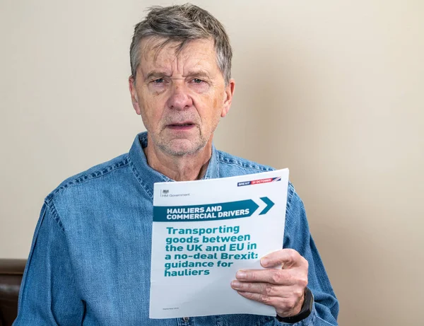 Senior caucasian truck driver reading Brexit no deal rules for exporting — Stock Photo, Image