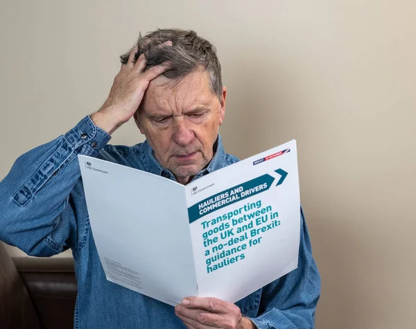 Senior caucasian truck driver reading Brexit no deal rules for exporting — Stock Photo, Image