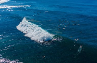 Oahu 'nun kuzey kıyısındaki Banzai Pipeline sahilinde birçok sörfçü var.