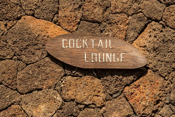 Old faded cocktail lounge sign painted on wood on stone wall — Zdjęcie stockowe