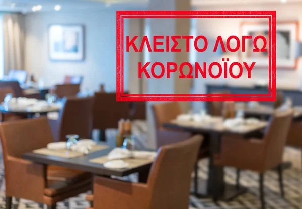 Modern restaurant with tables closed and sign in Greek saying Closed due to Coronavirus — Stock Fotó