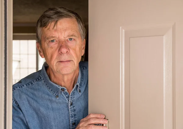 Senior man peering through front door for visitors during quarantine — Stock Photo, Image