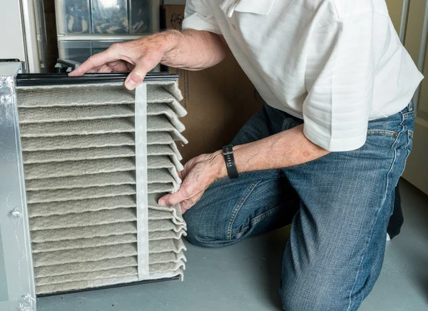 Homem sênior trocando um filtro de ar sujo em um forno HVAC — Fotografia de Stock