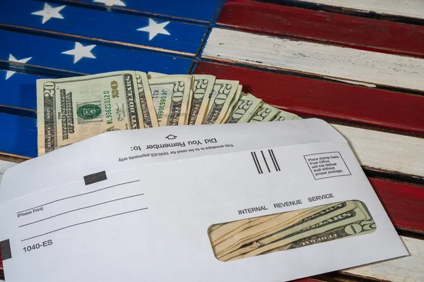Иллюстрация выплаты федерального стимулирования налоговой службой США наличными на флаге США — стоковое фото