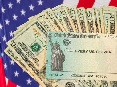 Milli Gelirler İdaresi 'nden gelen ve Amerikan bayrağı üzerinde nakit para bulunan federal uyaran ödeme çekinin resmi.