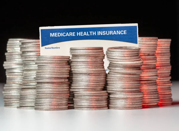 Pilhas de moedas de prata com cartão de seguro de saúde medicare para ilustrar dificuldades de financiamento — Fotografia de Stock