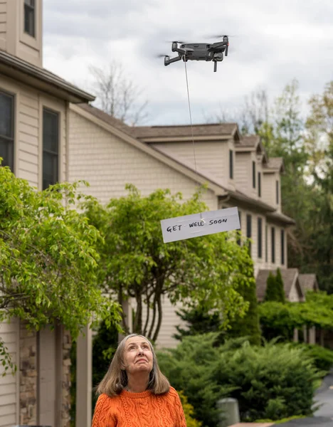 Drone delivering a get well soon message to isolated senior woman