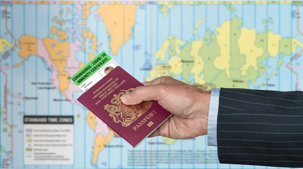 Mão caucasiana sênior segurando passaporte dos EUA com certificado de imunidade ao vírus contra mapa — Fotografia de Stock
