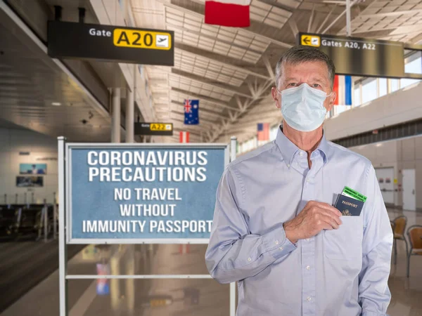 Bărbat în vârstă purtând mască de faţă şi purtând paşaport de imunitate la aeroport — Fotografie, imagine de stoc