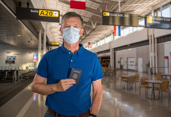 Senior mand iført ansigtsmaske som beskyttelse mod virus i lufthavnen - Stock-foto