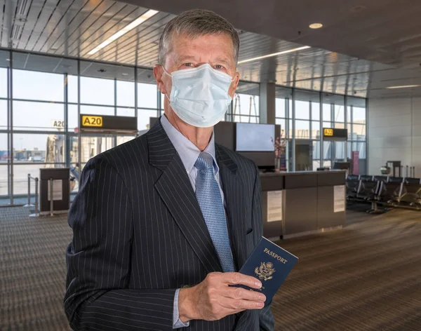 Senior mann med ansiktsmaske som beskyttelse mot virus på flyplassen – stockfoto