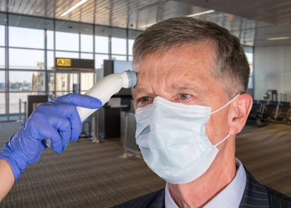 Bărbat în vârstă purtând mască de față având temperatura necesară pentru a verifica virusul la aeroport — Fotografie, imagine de stoc