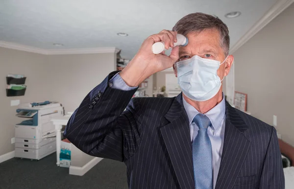 Hombre mayor usando mascarilla tomando su temperatura para comprobar si tiene fiebre — Foto de Stock