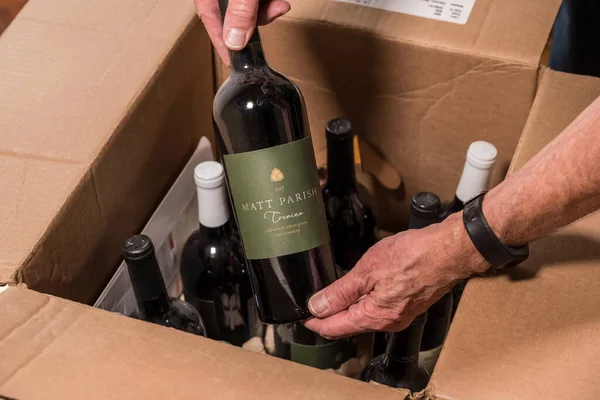 Senior man examining a case of wine from Naked Wines after home delivery — Stock Photo, Image