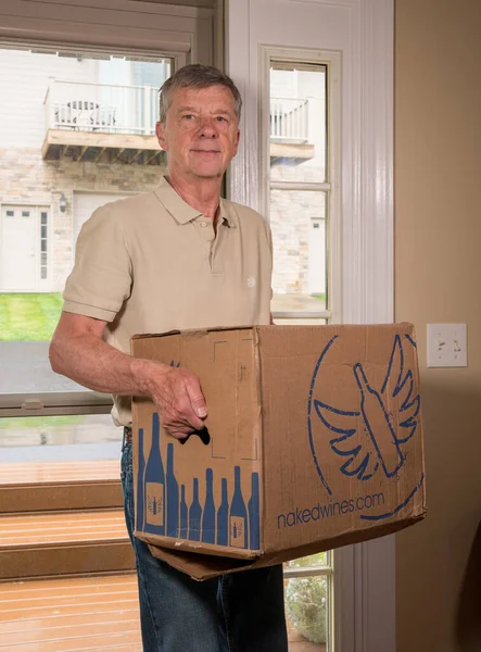 Hombre mayor llevando una caja de vino de Vinos Desnudos a casa —  Fotos de Stock