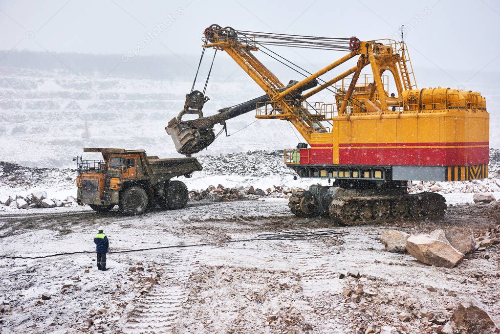 excavator loading granite or ore into dump truck at opencast