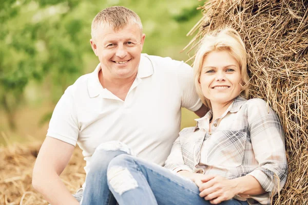 Усміхнена доросла пара біля стовбура сіна в сільській місцевості — стокове фото