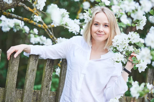 Femme adulte souriante avec fleur dans le jardin de printemps — Photo