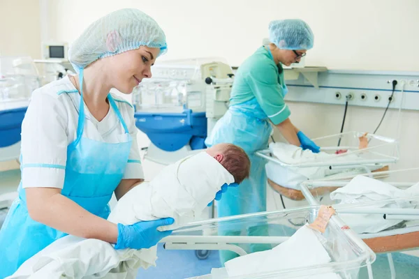 Молода медсестра, яка тримає новонароджену дитину в лікарні — стокове фото