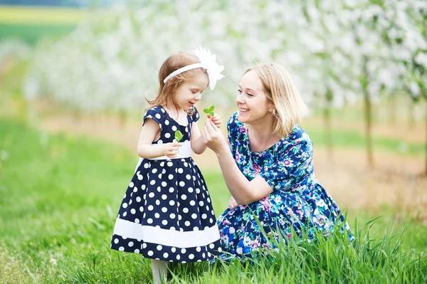 Anne ve kız bahar çiçek açan bahçesinde — Stok fotoğraf