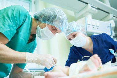 Yenidoğan resüsitasyonu. Doktor yeni doğan bebeğe yoğun terapi yapıyor.