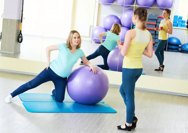 Pregnant woman doing fitness ball exercise with coach — Stock Photo, Image