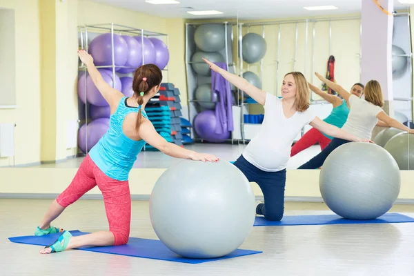 Gravid kvinna gör fitness boll träning med tränare — Stockfoto