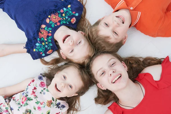 Gruppe lächelnder vier Kinder, die auf dem Boden liegen. von oben — Stockfoto