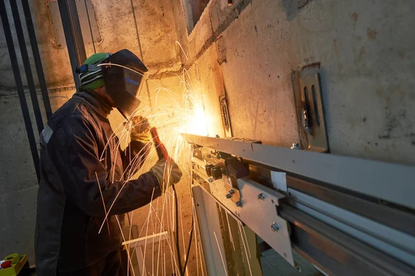 Lift worker welding elevator fasteners in lift shaft — Stock Photo, Image