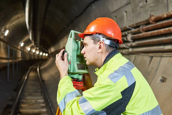 Agrimensor con nivel de teodolito en obras de construcción de túneles ferroviarios subterráneos —  Fotos de Stock