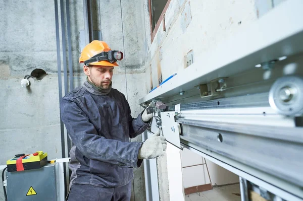 Machinist met spanner lift aanpassingsmechanisme in de liftschacht — Stockfoto