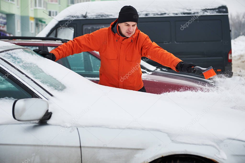 man cleaning car from snow