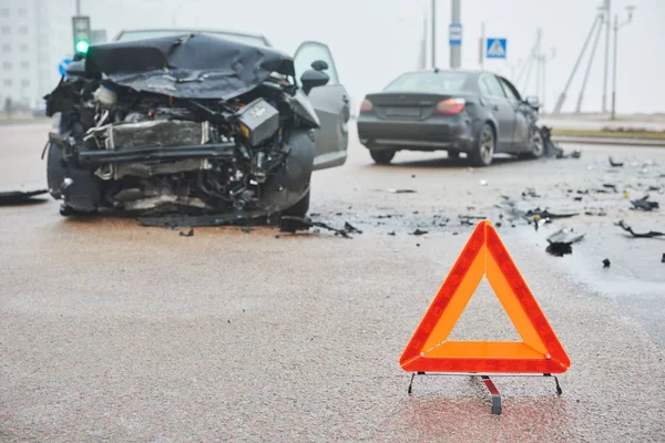 Accidente o accidente con dos automóviles. Señal de triángulo de advertencia vial en foco — Foto de Stock