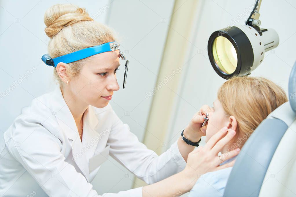 female doctor of ENT ear nose throat at work examining girl nose