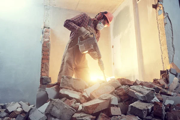 Строитель с разбивающей молотком стеной в помещении — стоковое фото