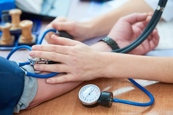 Physician doctor is checking the blood pressure of the patient — Stock Photo, Image