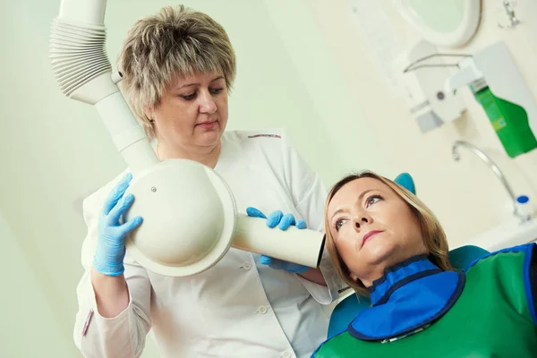 Dentista opera unidad de rayos X intraorales dentales para la imagen dental con el paciente —  Fotos de Stock