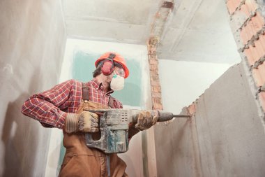 Yıkıcı çekiçli işçi iç duvarı yıkıyor.
