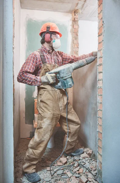 Строитель с разрушающим молотком нарушающим внутреннюю стену — стоковое фото