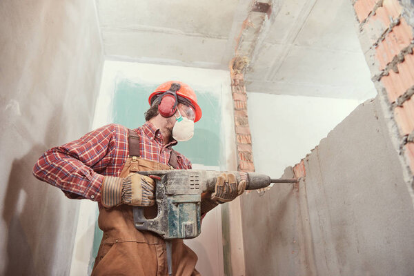 worker with demolition hammer breaking interior wall